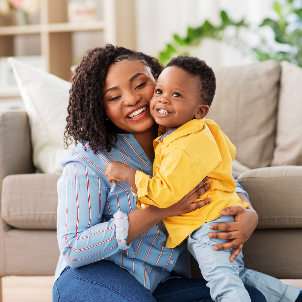 A mother holding her smiling child at home, symbolizing safety and a path forward